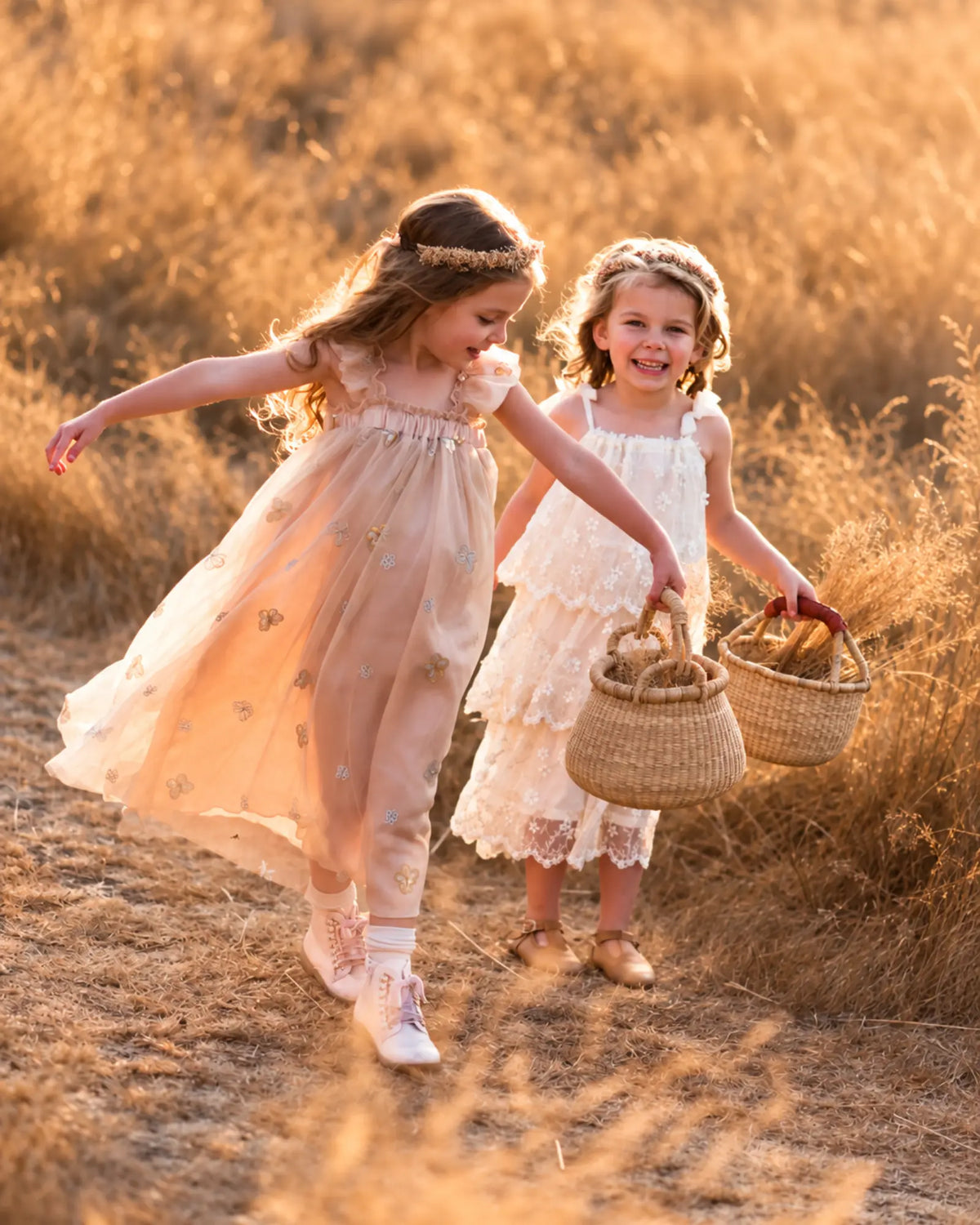 Two young girls carrying handwoven Bolga baskets while walking together through a sunlit meadow.