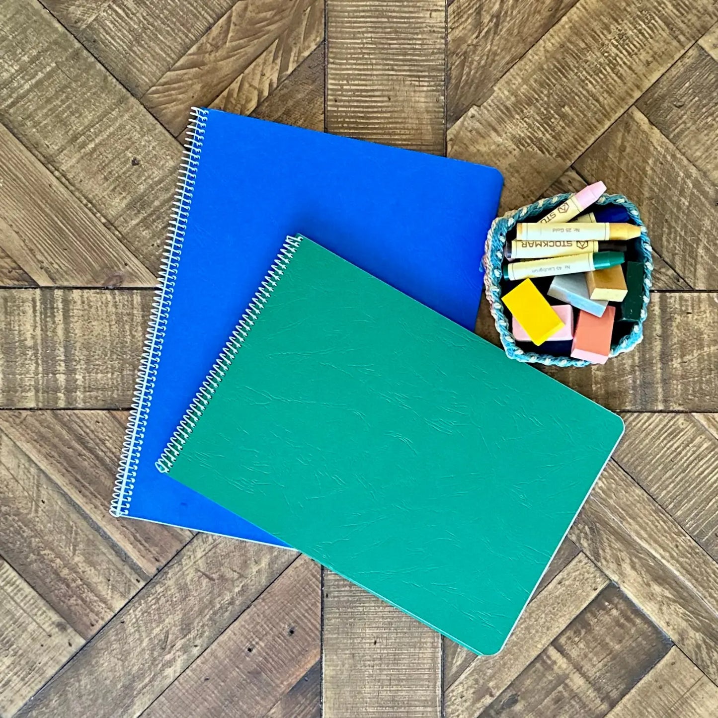 Blue and green Book of Centuries lesson books arranged with colorful wax crayons