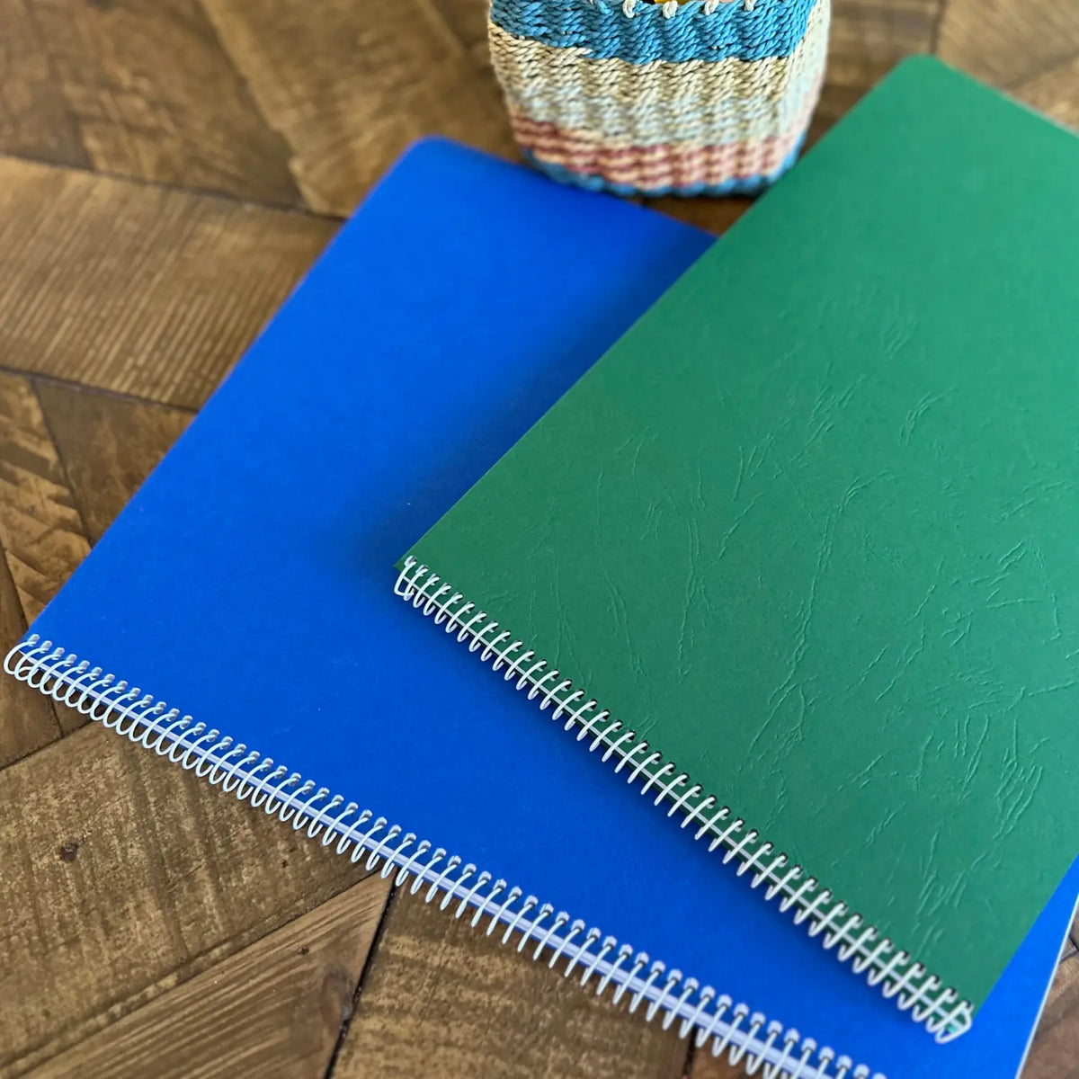 Green elementary and blue upper-grade Book of Centuries books stacked on a wooden table