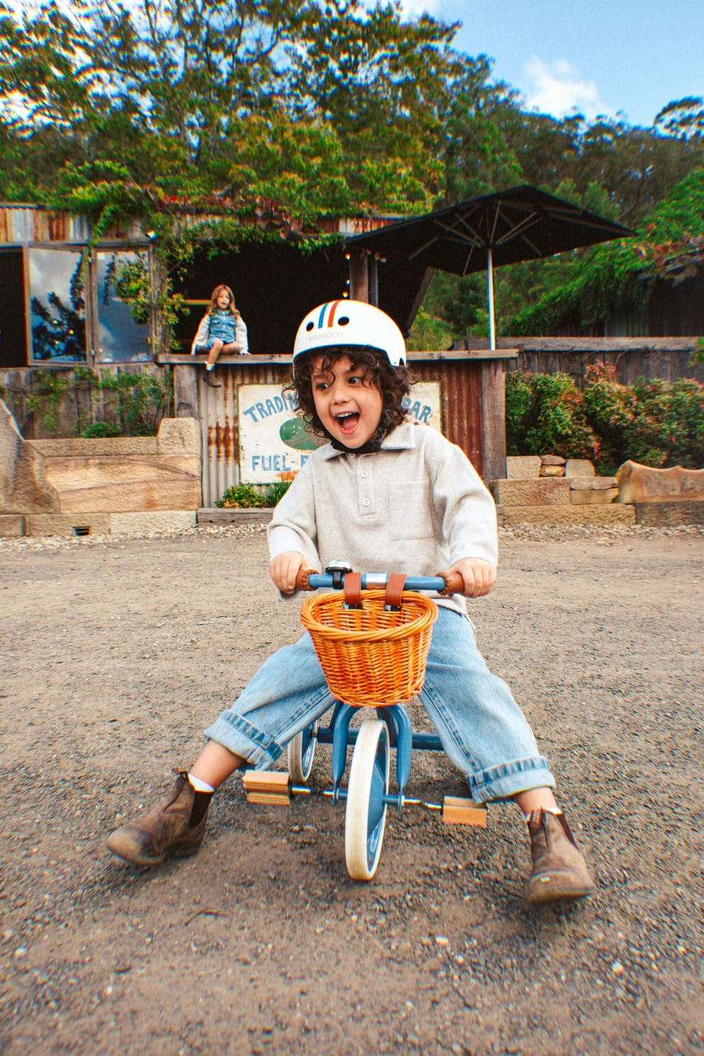 Child riding a tricycle with a basket in an outdoor setting
