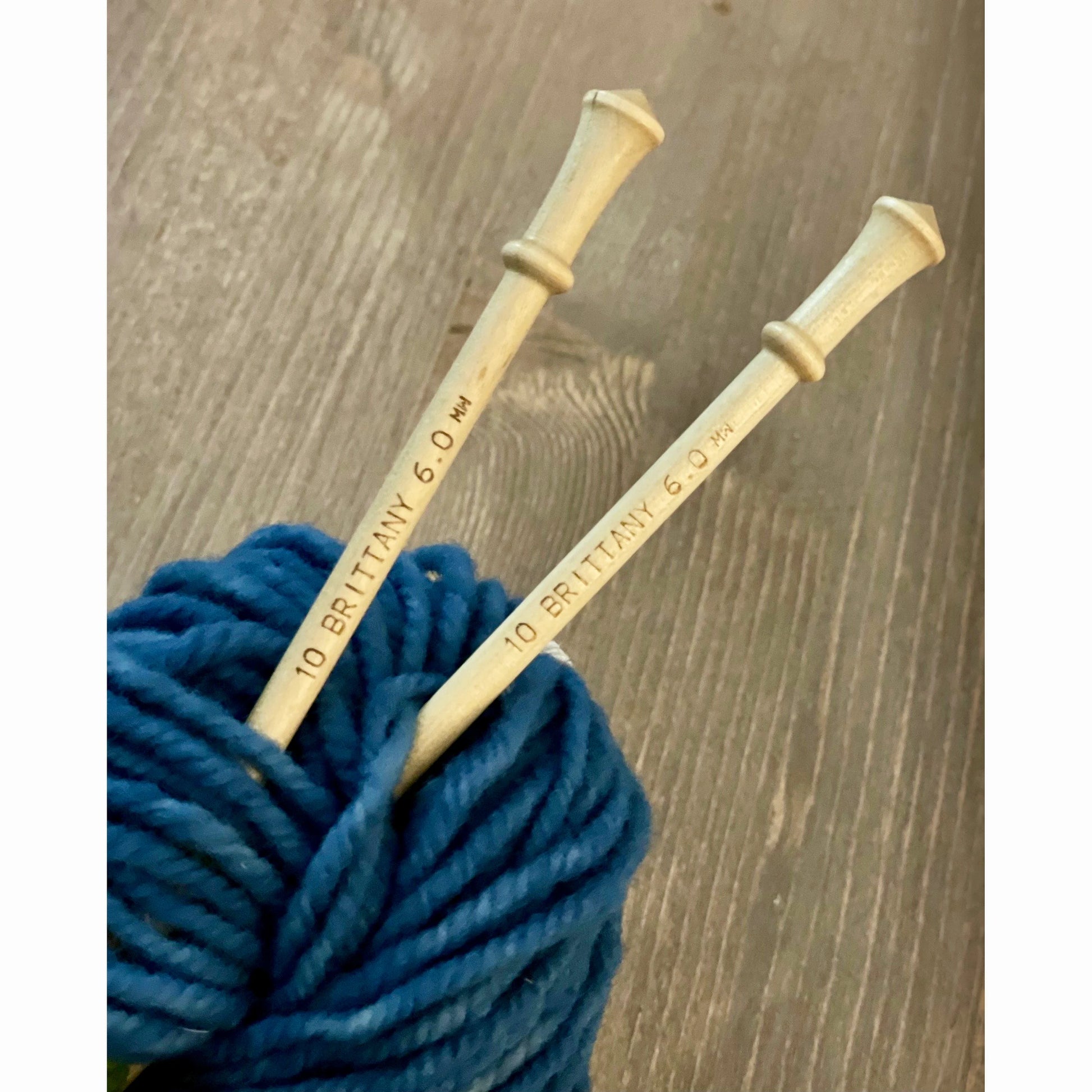 Brittany birch wood knitting needles placed with bright blue wool yarn