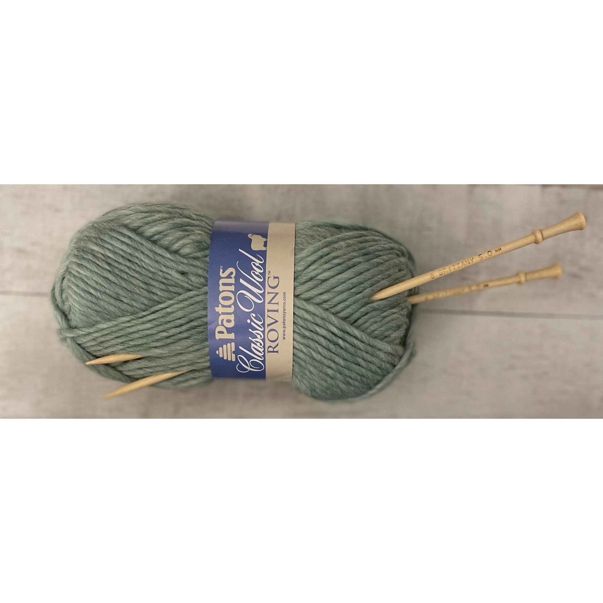 Brittany birch wood knitting needles resting on gray-green wool yarn