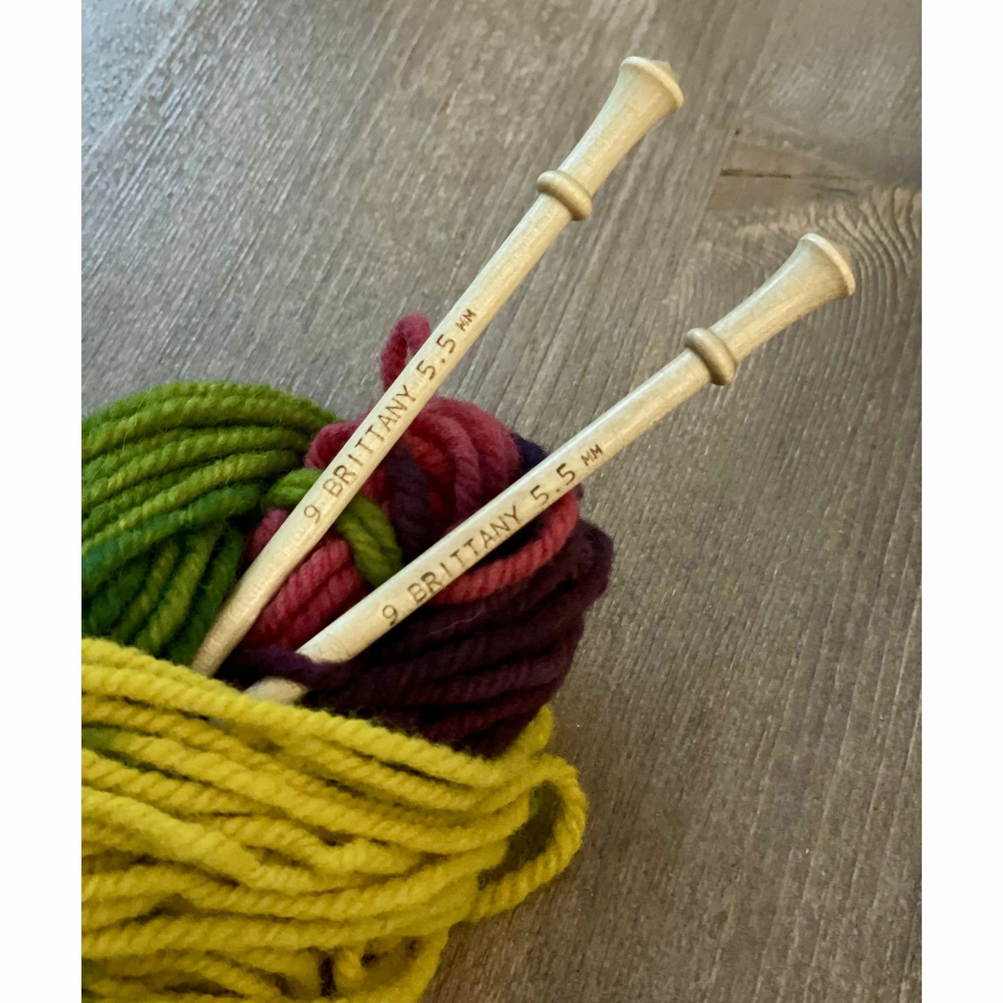 Brittany birch wood knitting needles standing in a basket of colorful wool yarn
