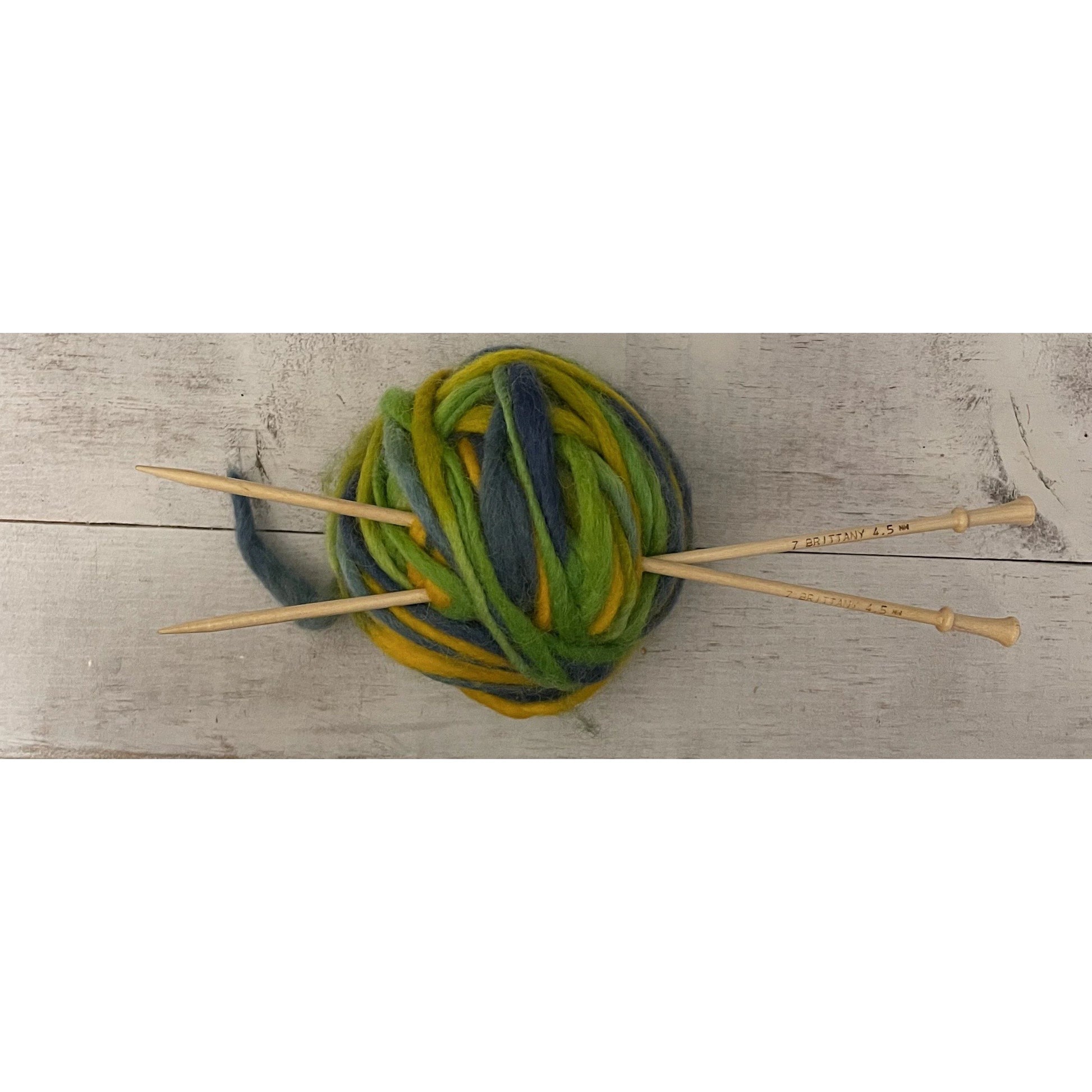 Brittany birch wood knitting needles tucked into a ball of green variegated wool yarn