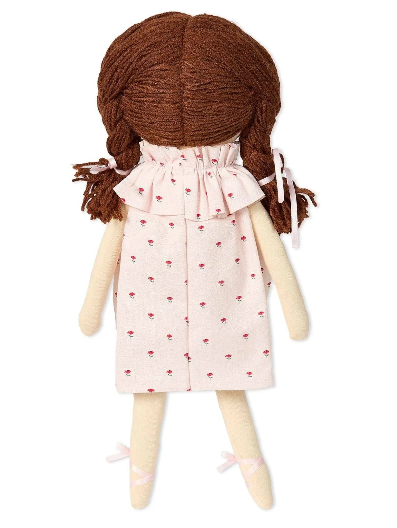 Doll with braided brown hair wearing a pink dress with red patterns on a white background