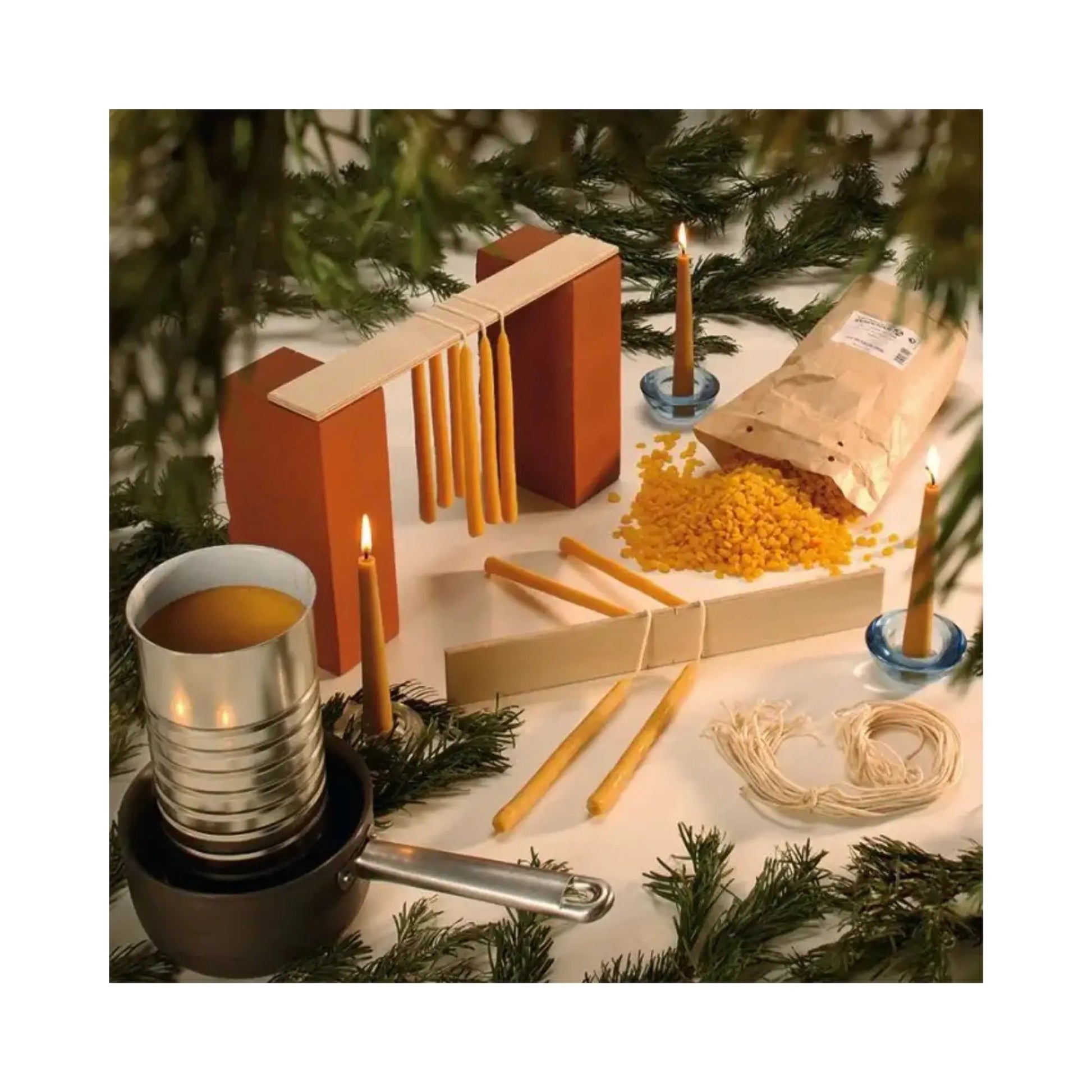 Candle-making materials and tools on a table with a Christmas tree in the background