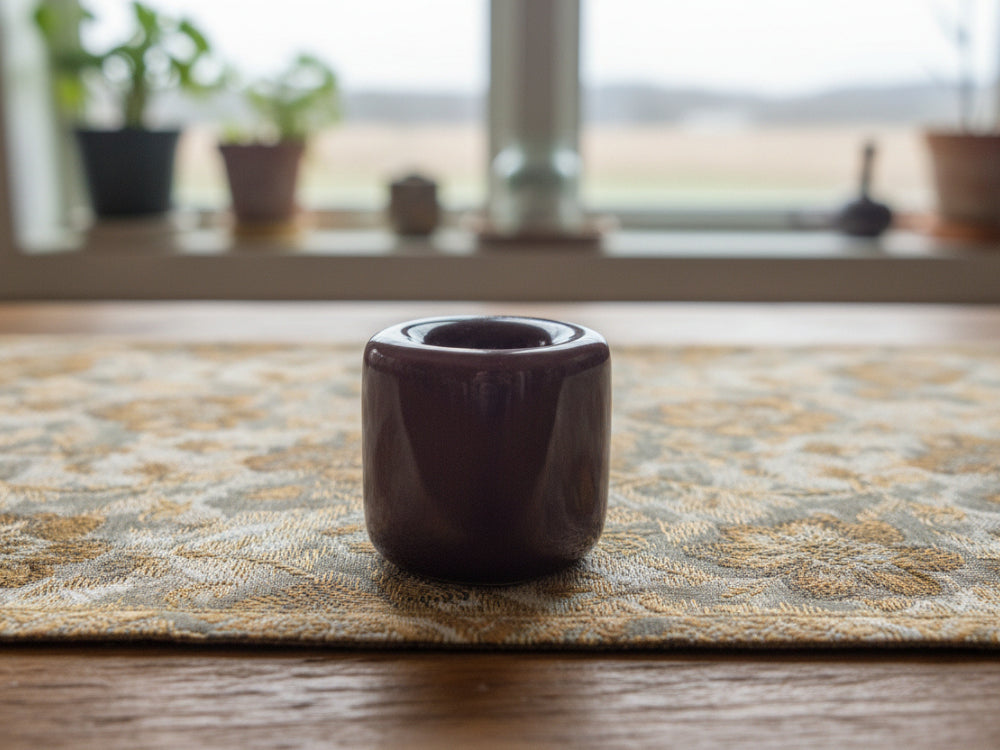 Purple taper candle holder on a wooden table with window in the background