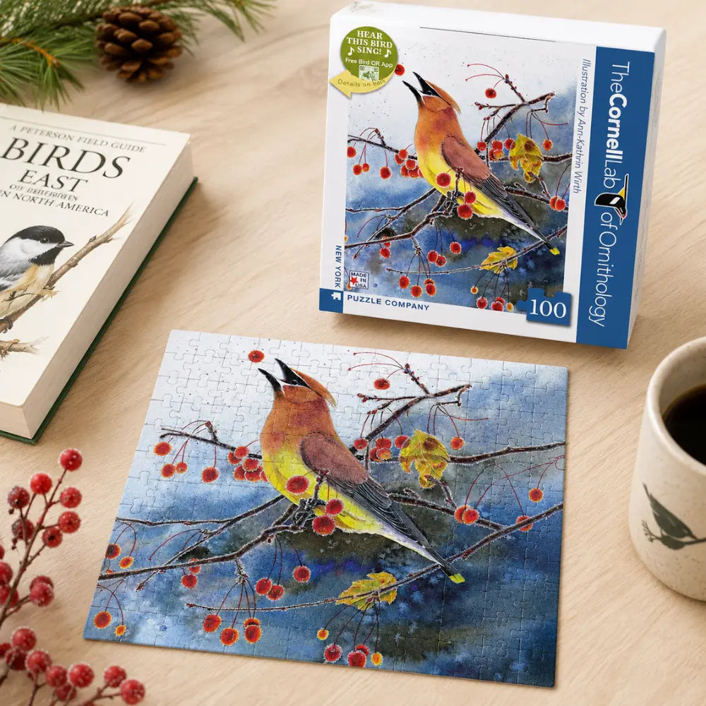 Cedar Waxwing 100 Piece Mini Puzzle shown completed beside the puzzle box, bird field guide, red berries, and coffee mug