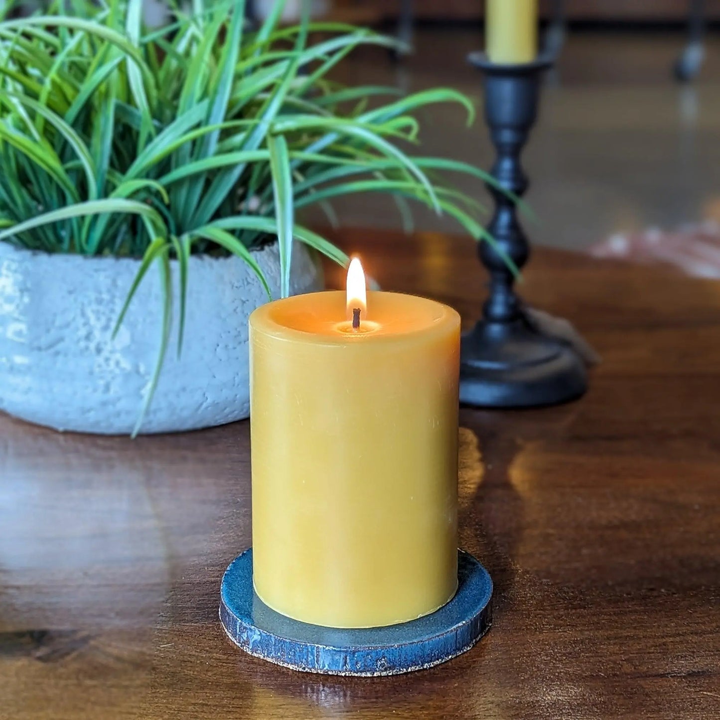 Glazed ceramic pillar candle base holding a beeswax pillar candle on a wooden table