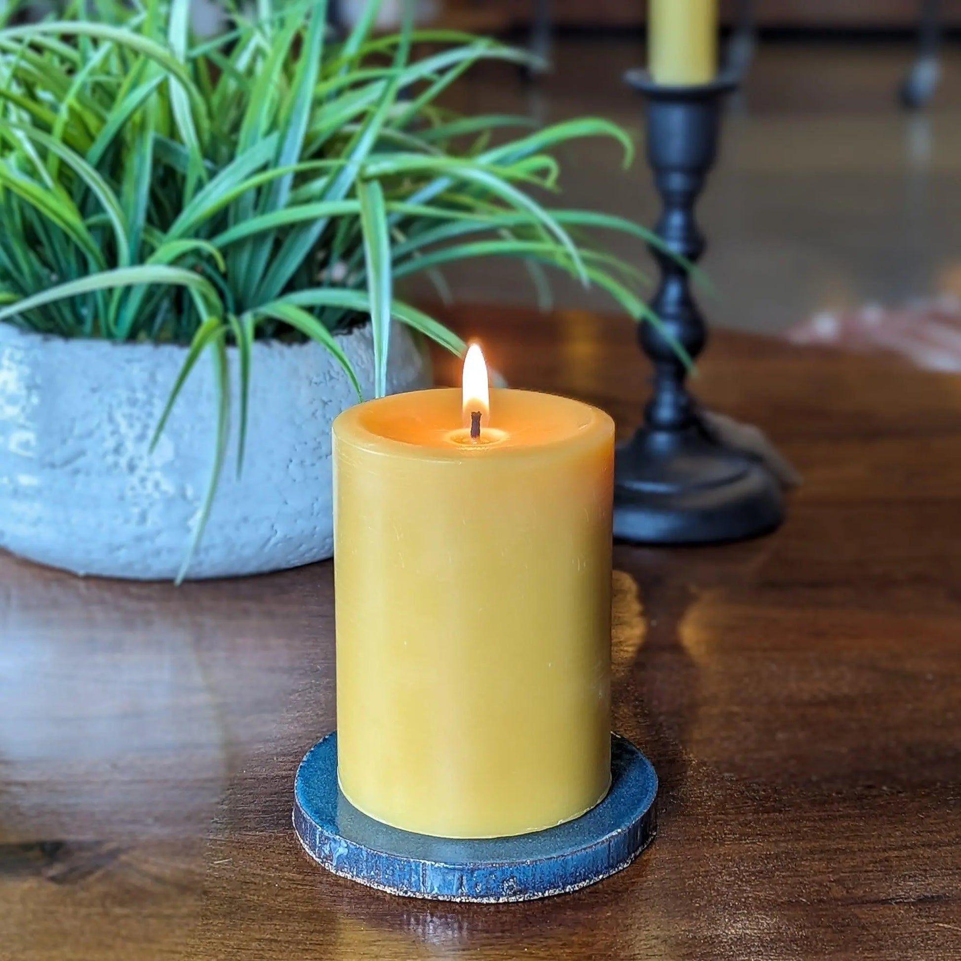 Glazed ceramic pillar candle base holding a beeswax pillar candle on a wooden table