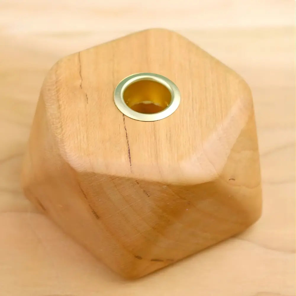 Wooden hexagonal candle holder with a central hole on a beige background