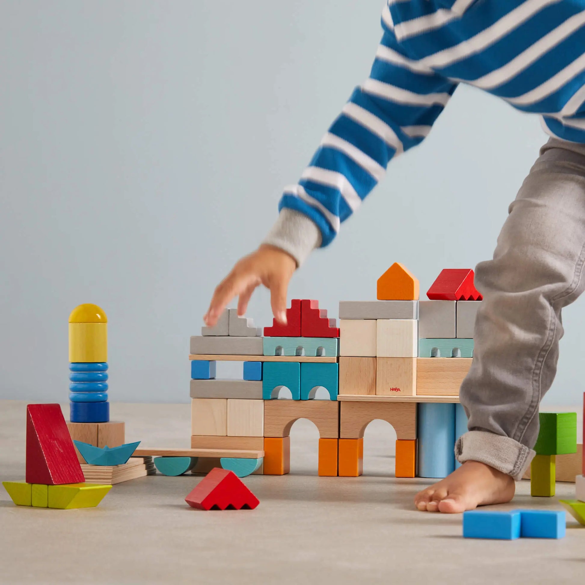 Child playing with colorful building blocks on a light surface.