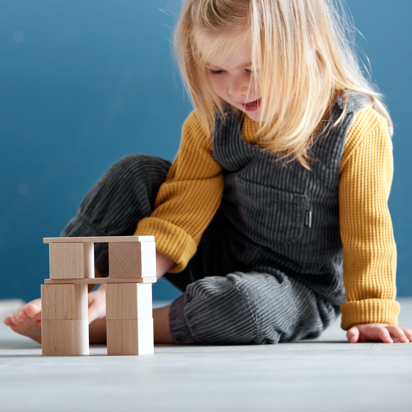 Child building a structure with wooden building blocks during floor play