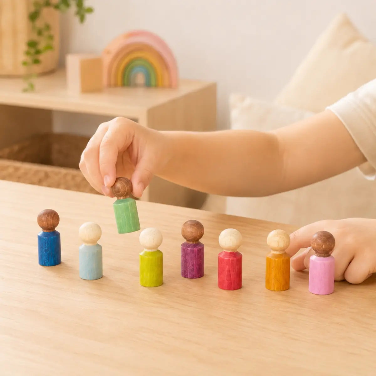 Child’s hands arranging eight colorful Lubulona Lubu People wooden figures for small world play