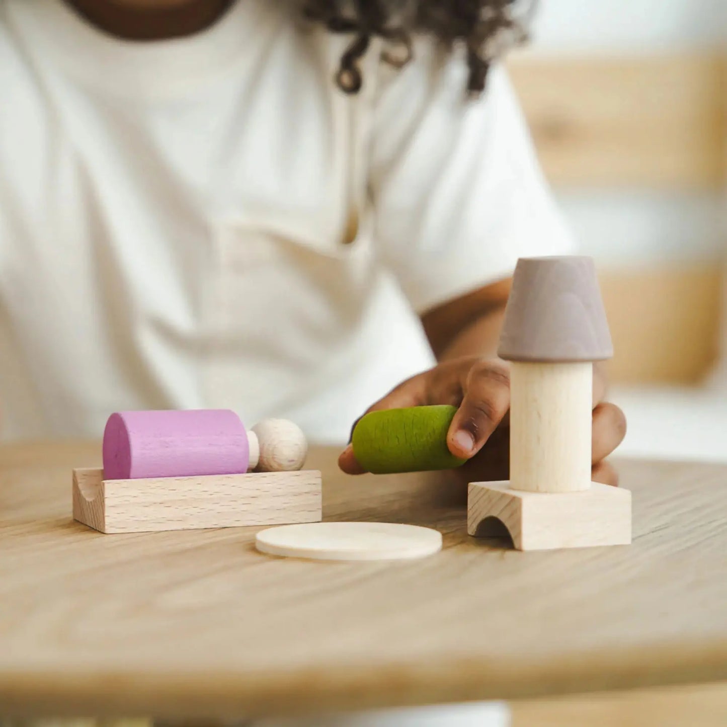 Child arranging the Pink Lubulona My Room peg doll and wooden furniture for small world play