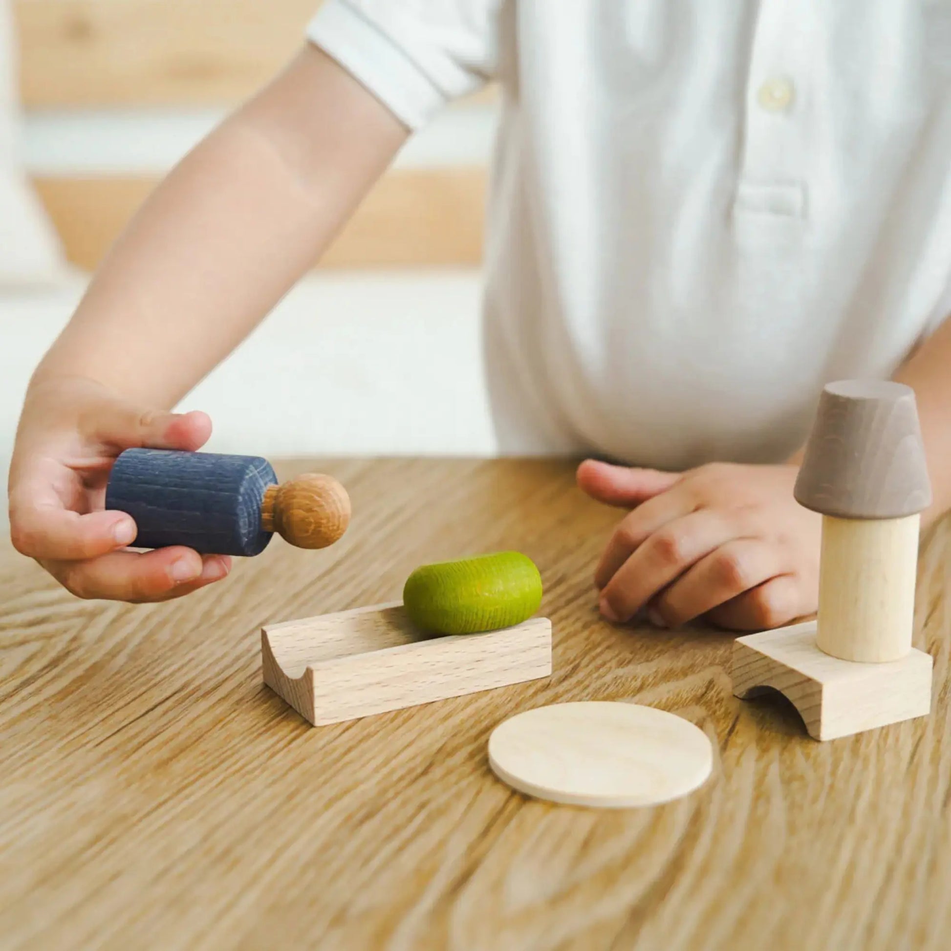 Child arranging the Thunder Grey Lubulona My Room peg doll and wooden furniture