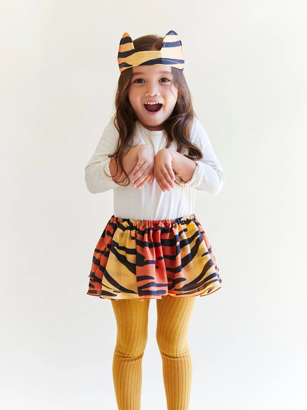 A young girl playing and wearing a tiger-print headband and matching tiger tutu