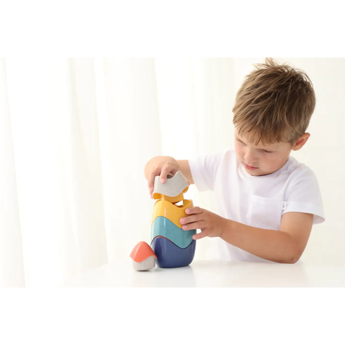 Child playing with a colorful toy on a white background