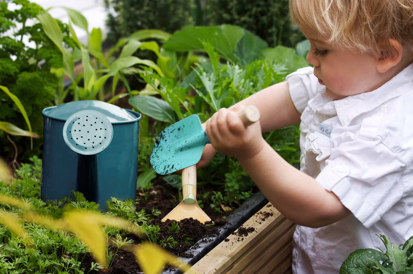 Child playing with gardening tools in a garden