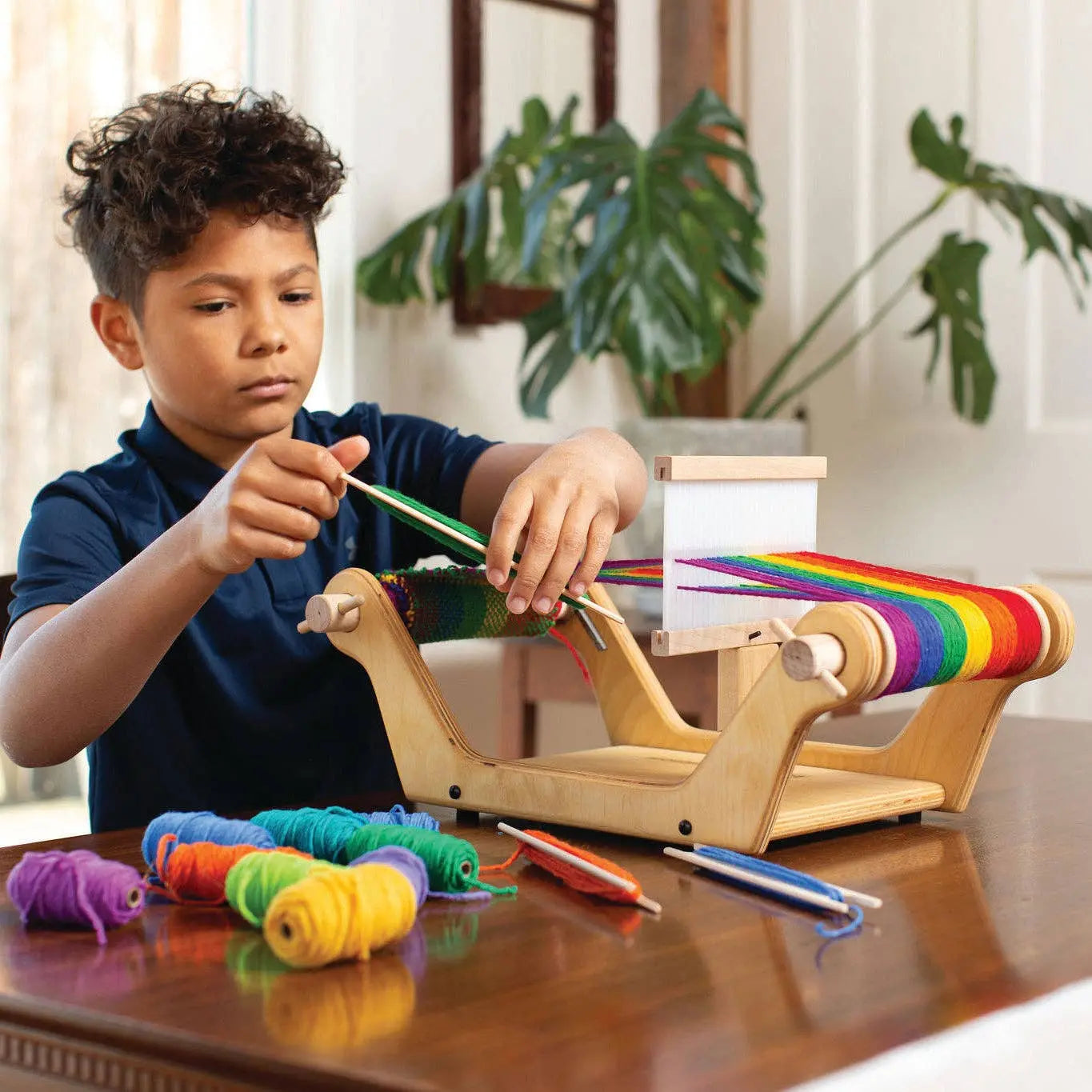 Child using a wooden table loom to weave with colorful wool yarn