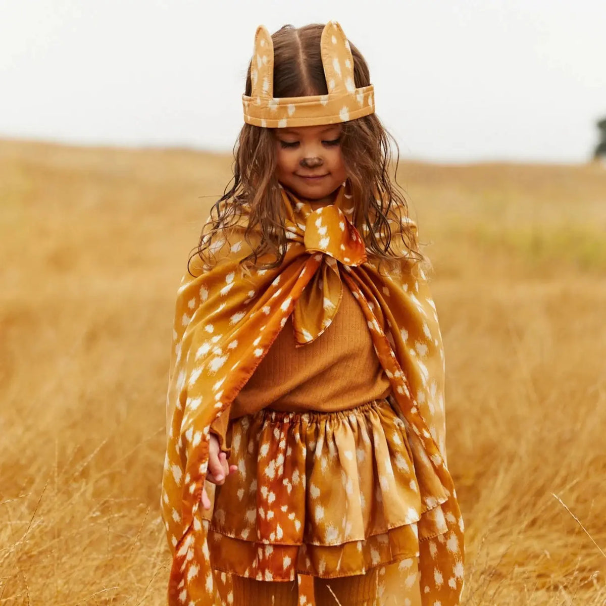 Child wearing a fawn-print Playsilk as a cape with matching fawn ears