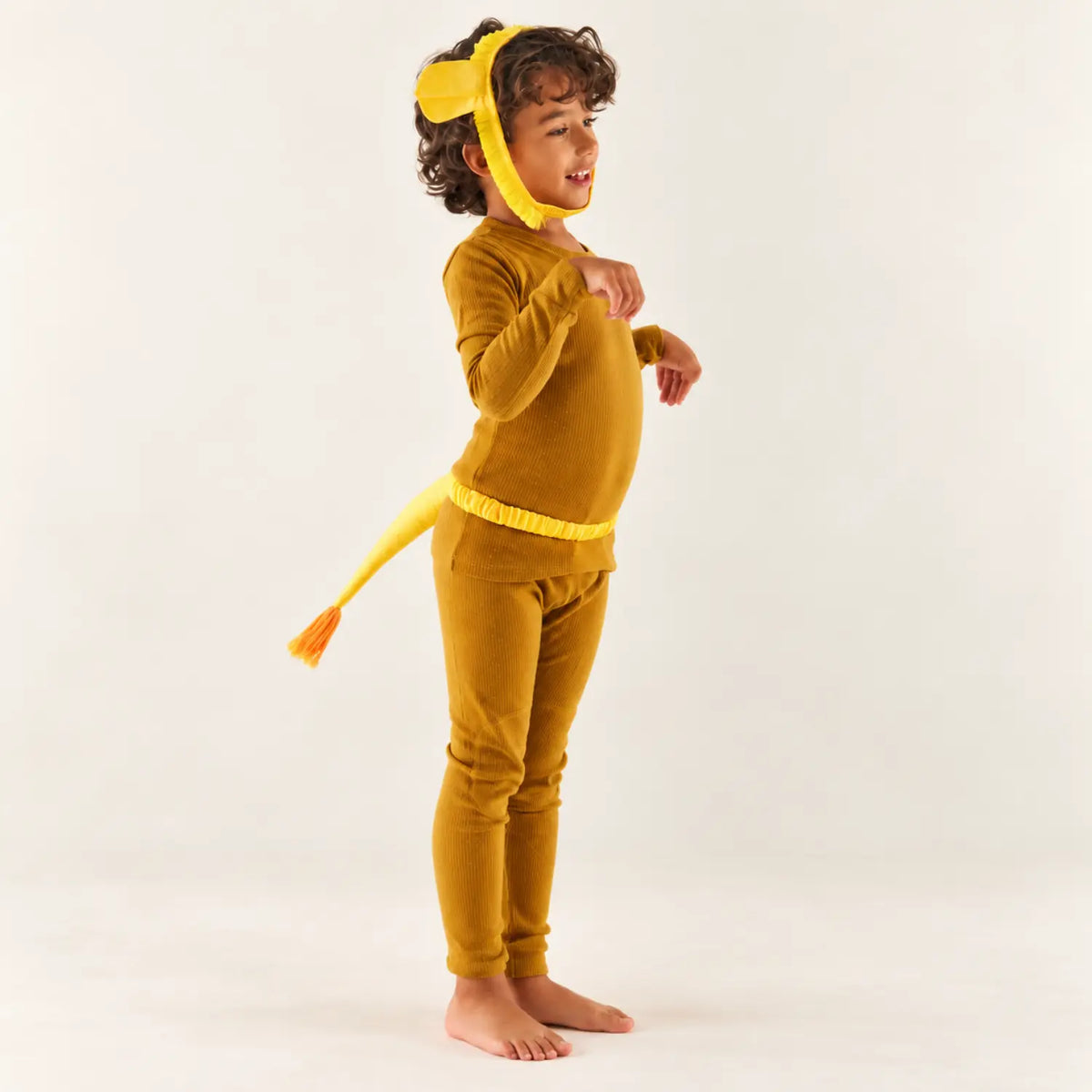 Child standing in a lion dress-up costume wearing a yellow lion tail and lion ears