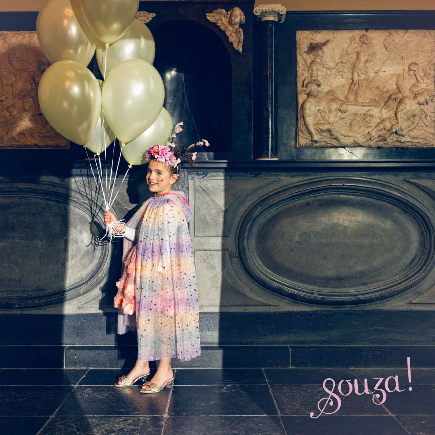 Child wearing rainbow dress-up cape for storytelling and imaginative play