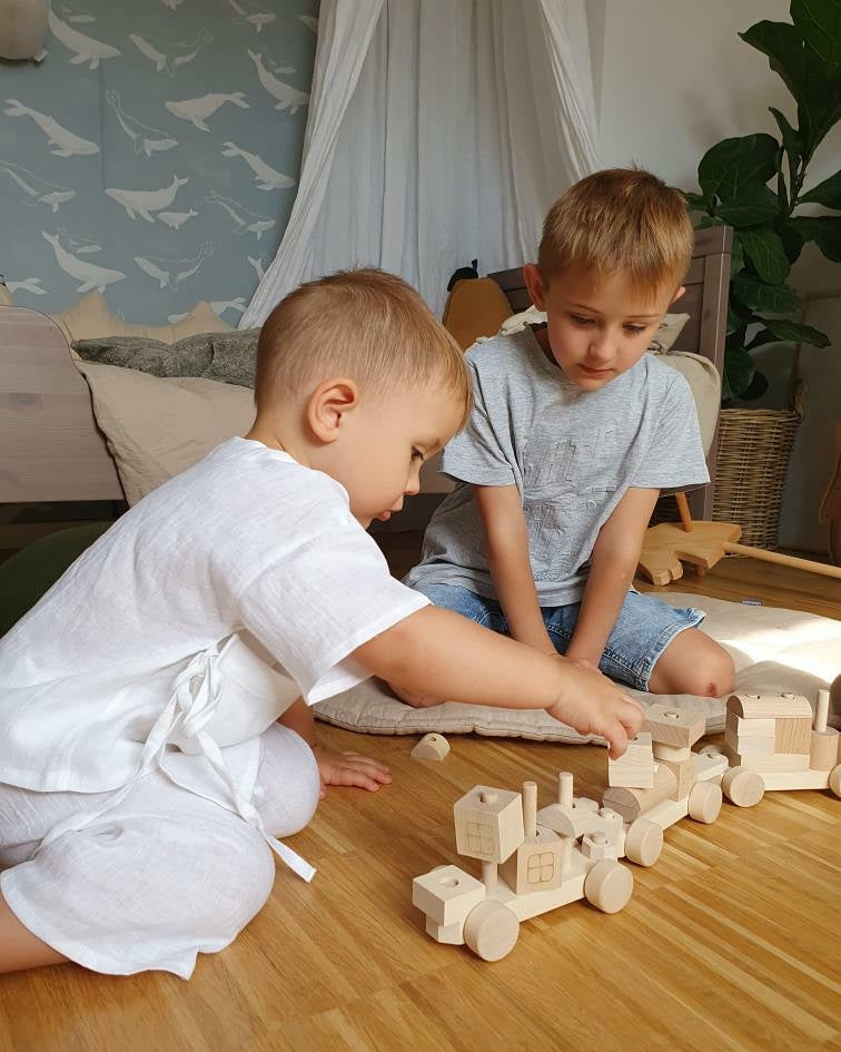 Children playing with natural wooden train and block set on the floor