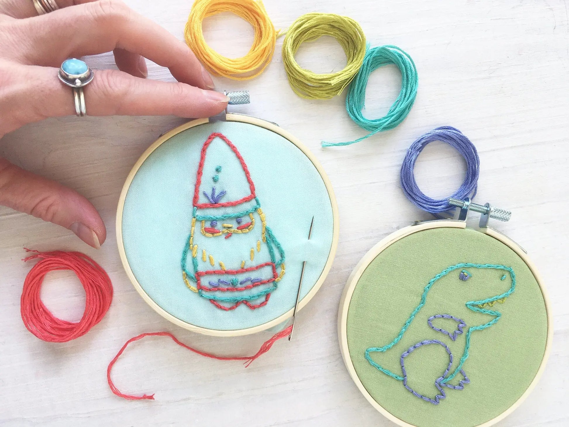 Embroidery hoops with colorful thread and a gnome design on a white surface