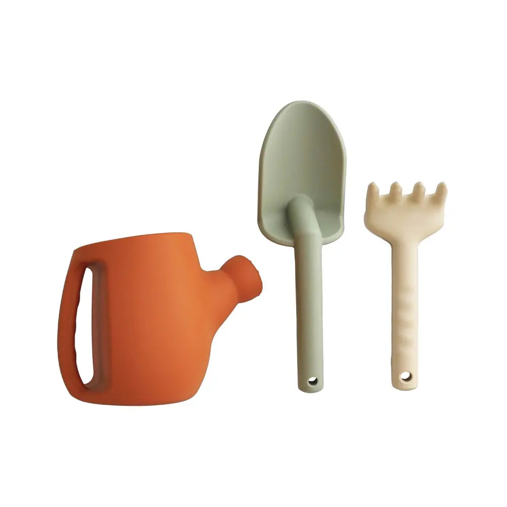 Set of colorful children's silicone gardening tools including a watering can, spade, and fork on a white background