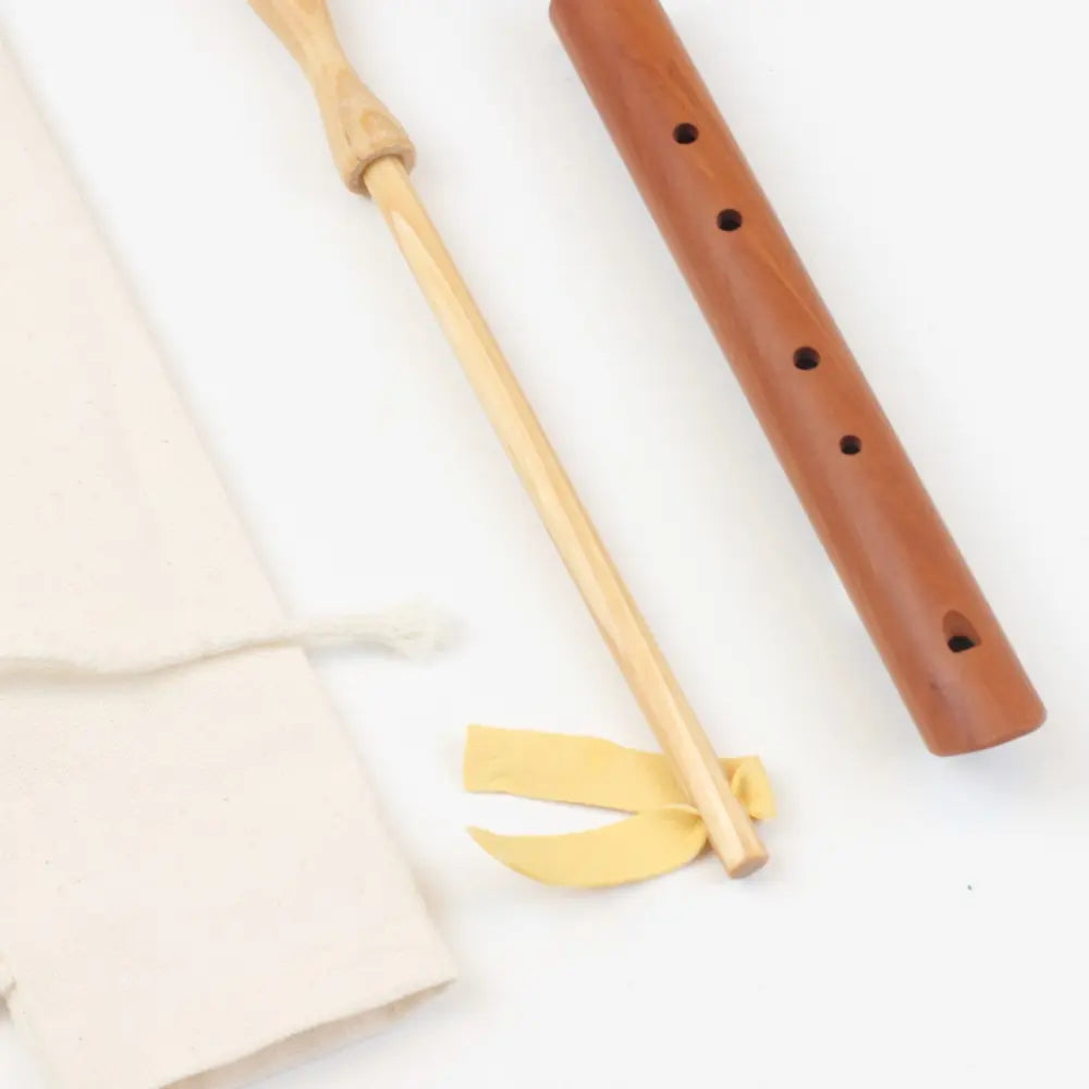A Choroi wooden pentatonic flute with wooden swab and cotton bag on a white background