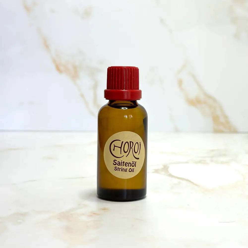 Bottle of Chori String Oil with a red cap on a marble surface