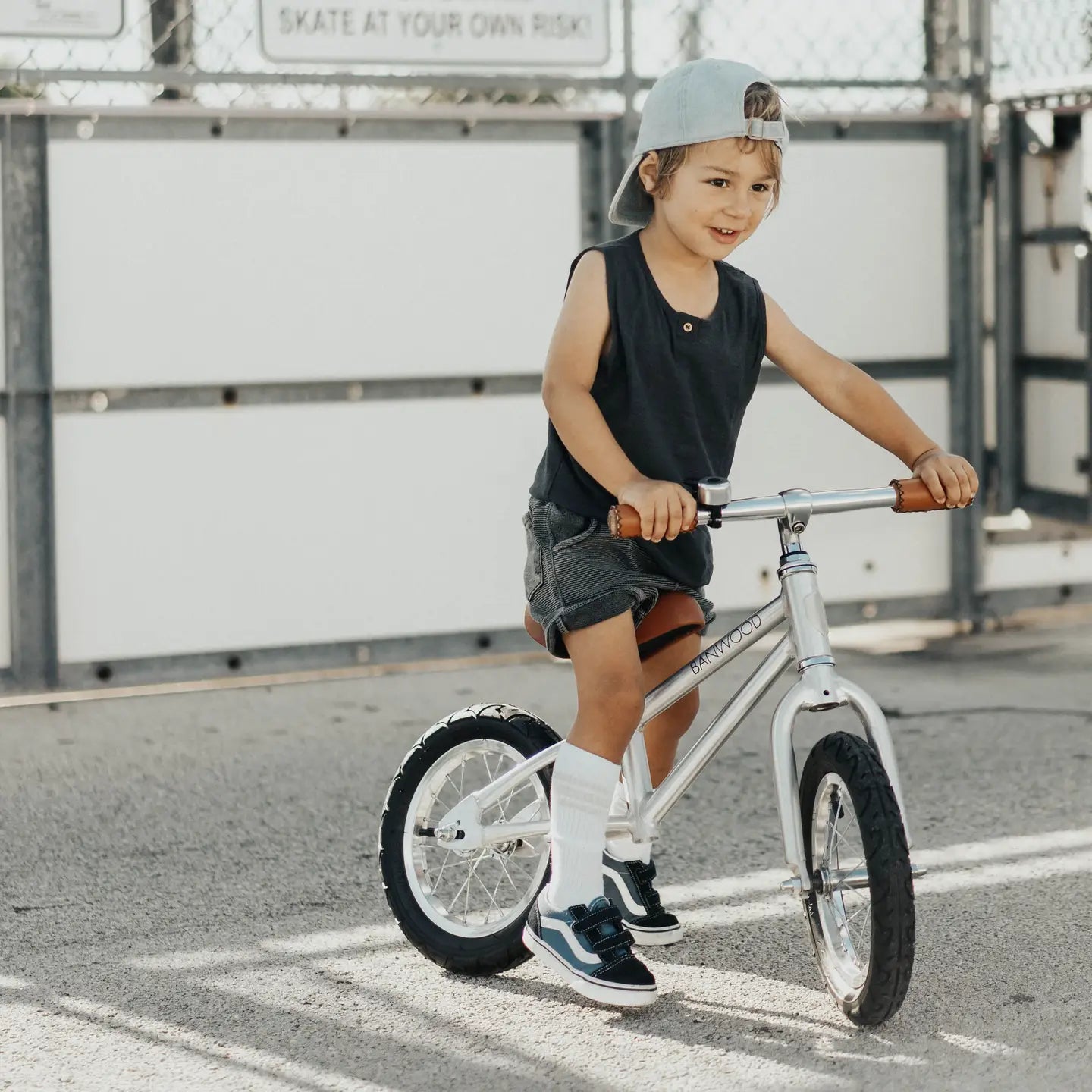 Child riding a balance bike outdoors with a neutral background