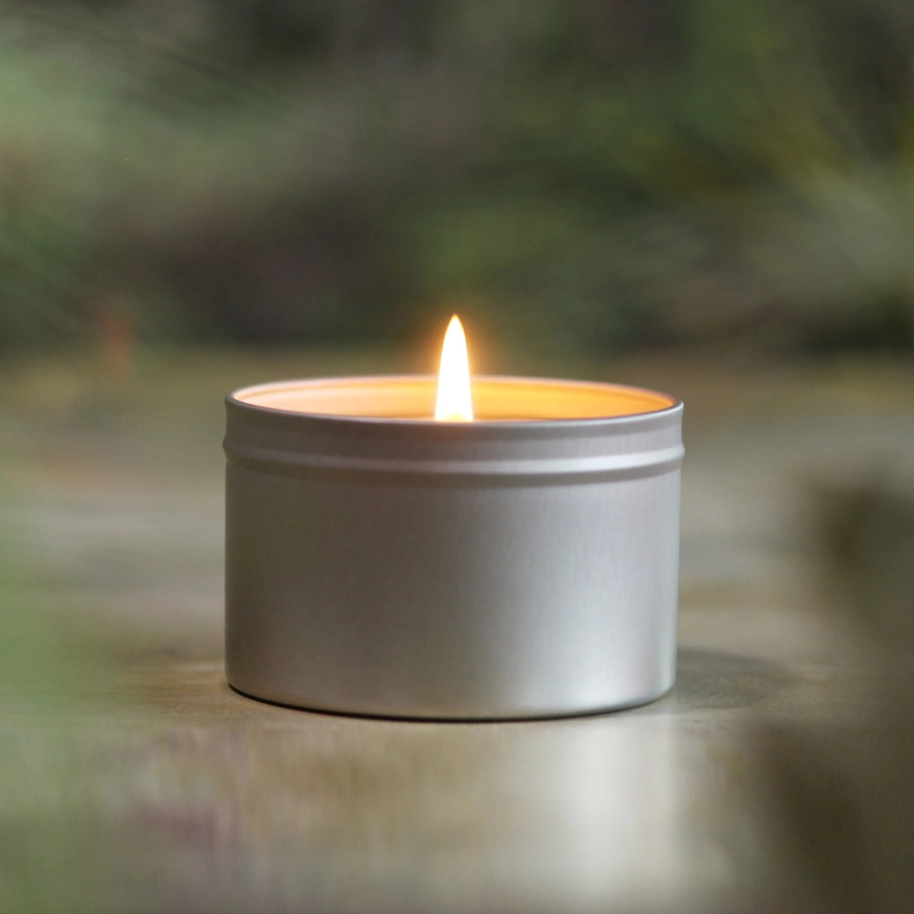 Natural Citronella Candle in a metal tin on a blurred background