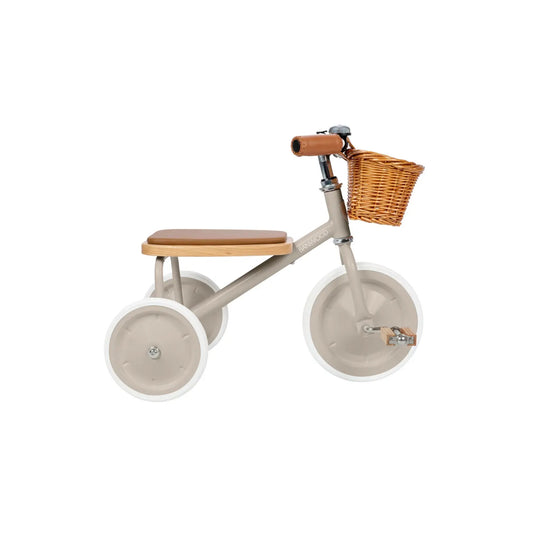 Children's beige tricycle with a brown seat and wicker basket on a white 