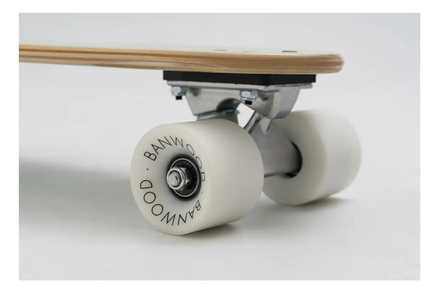 Close-up of a skateboard with white wheels on a light gray background