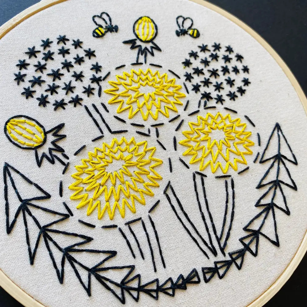 Close-up of beginner dandelion embroidery with yellow flowers and bee details