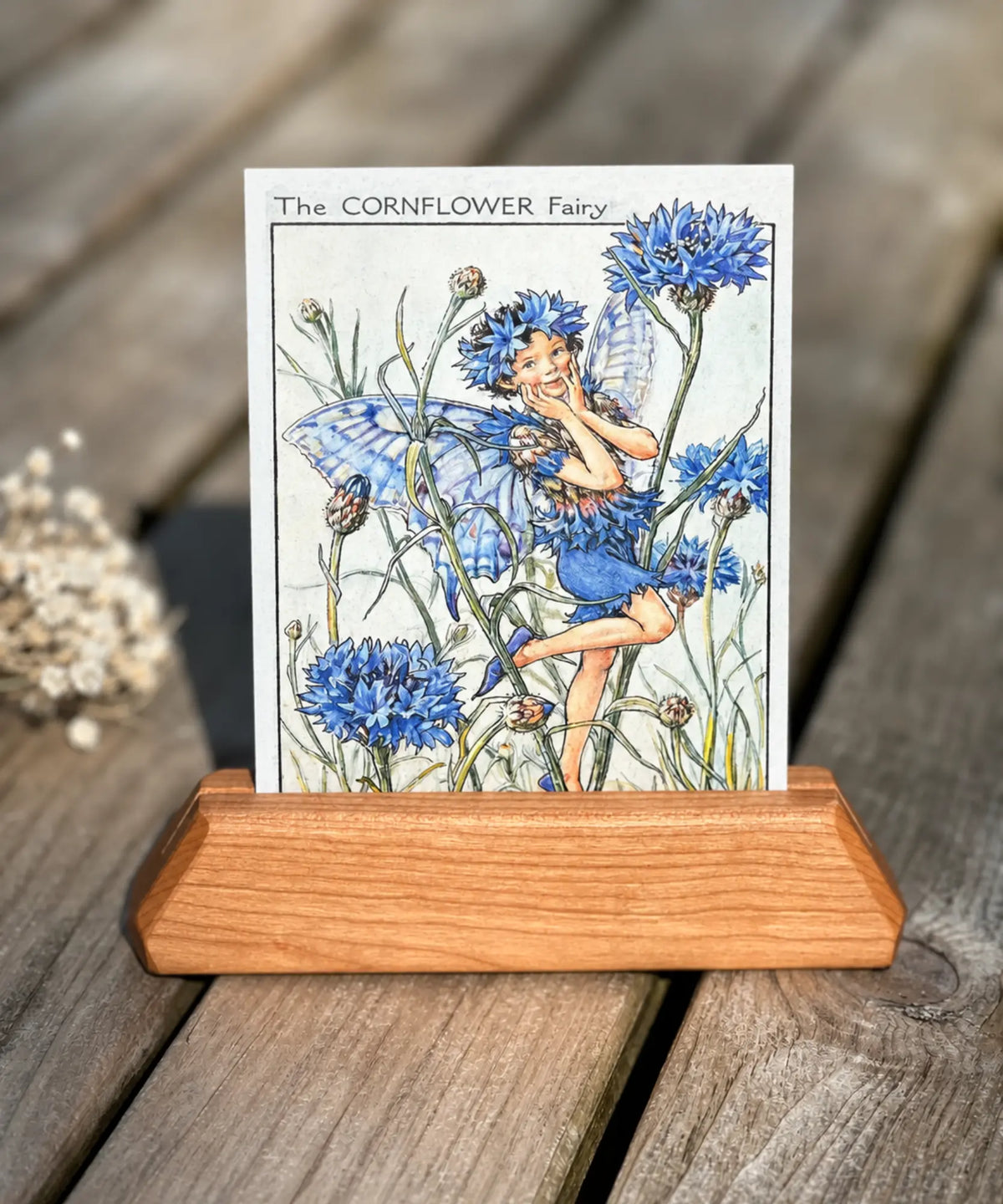 The Cornflower fairy by Cicely Mary Barker in a wooden stand on a rustic wooden table