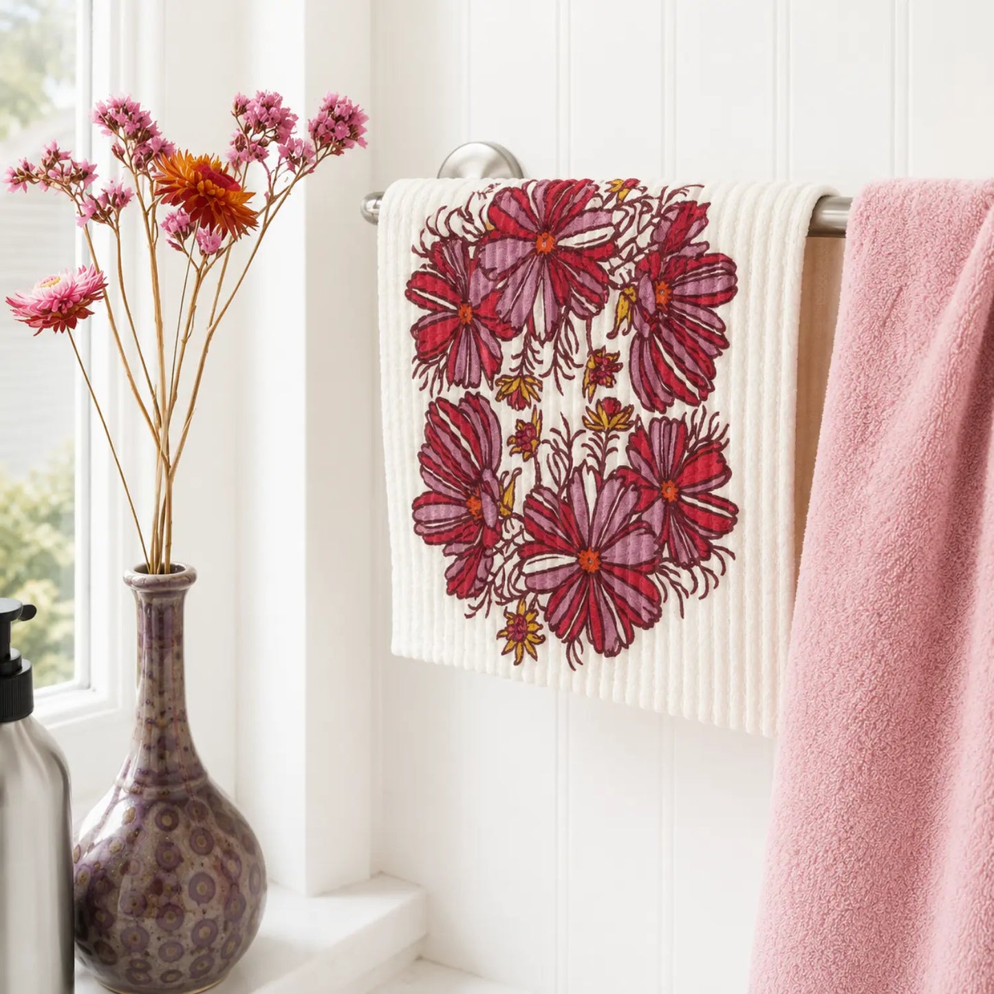 Cosmos flower Swedish dishcloth hanging beside a pink towel in a bright kitchen