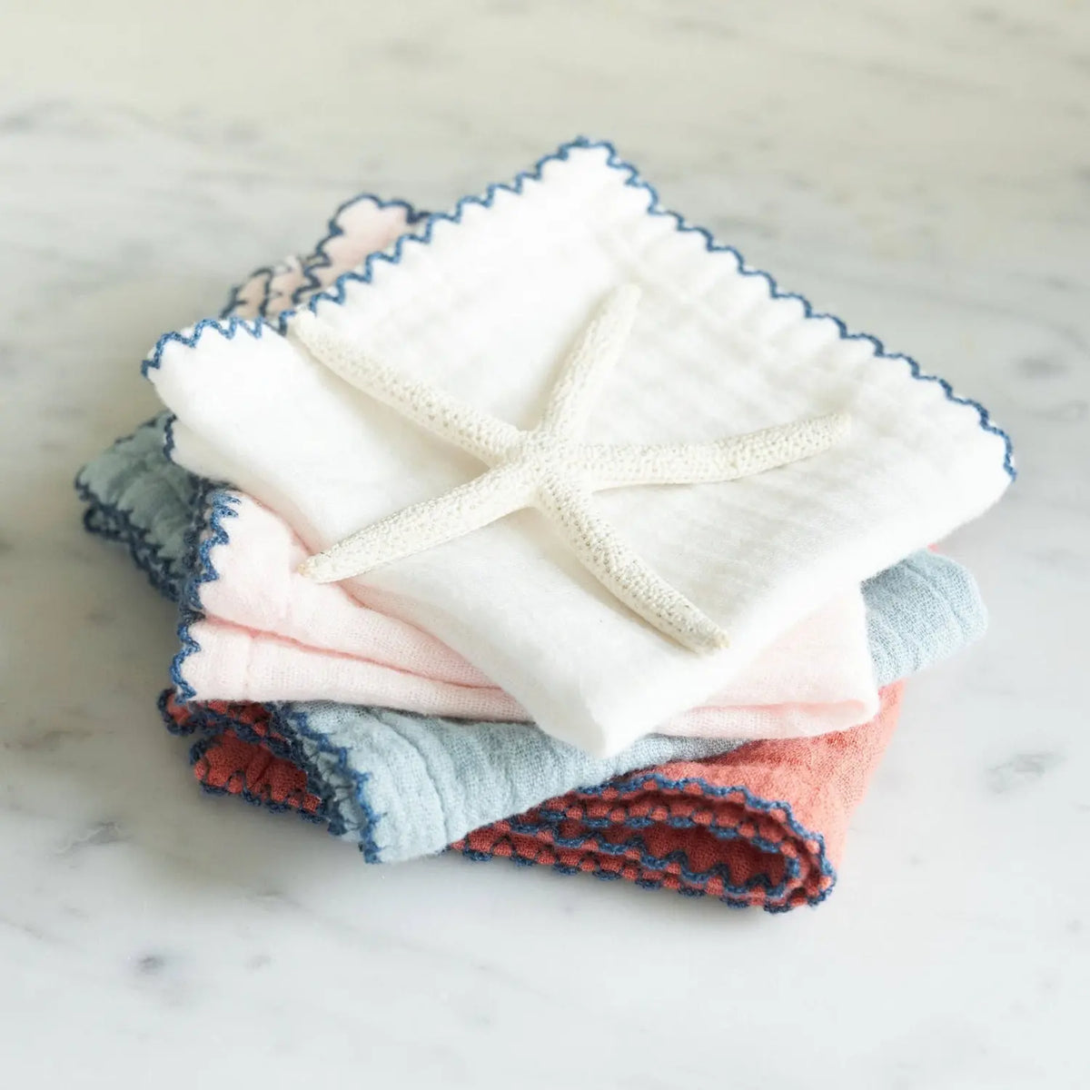 Stack of soft Babette cotton baby washcloths with scalloped edging and decorative starfish