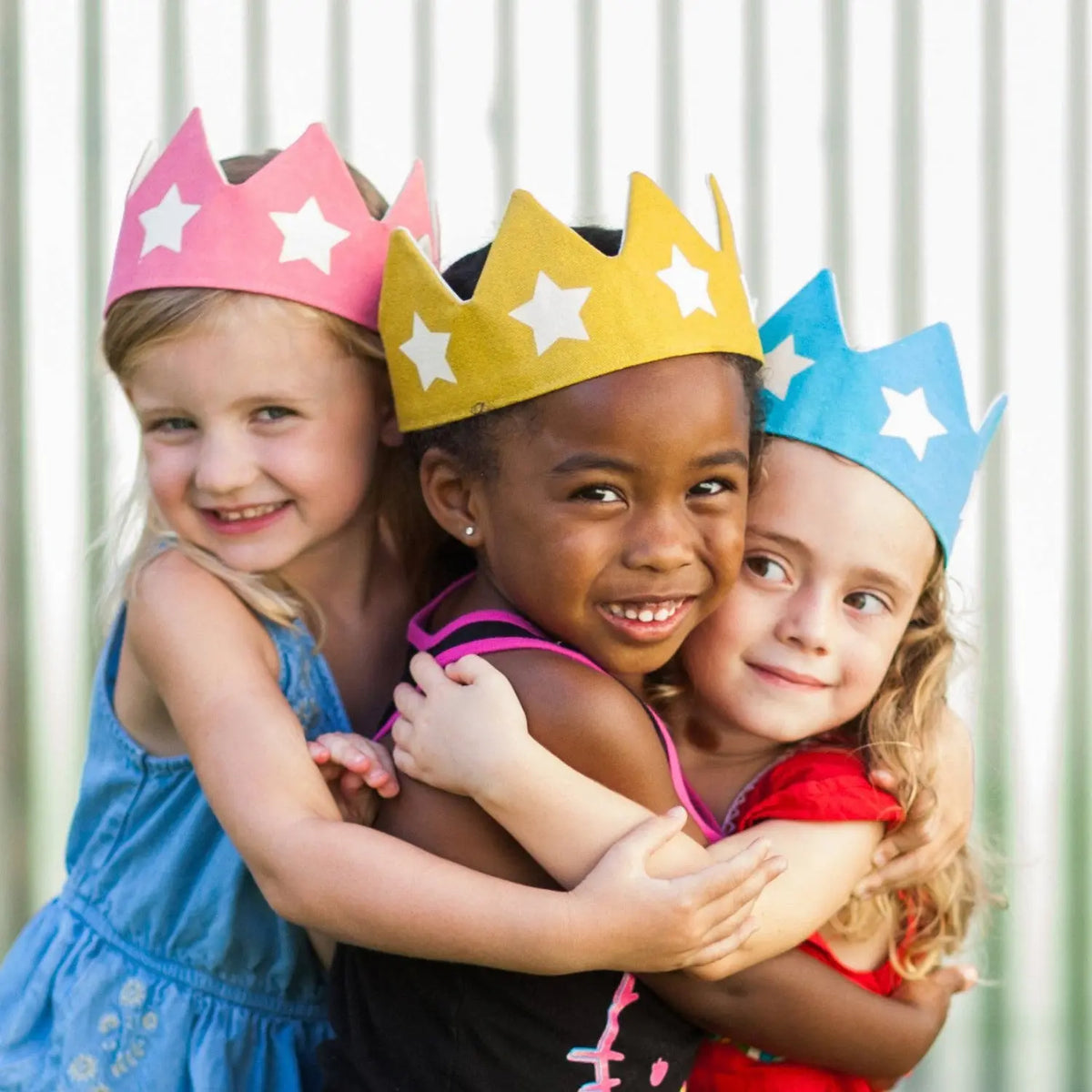 Three children wearing pink, gold, and blue cotton canvas star crowns