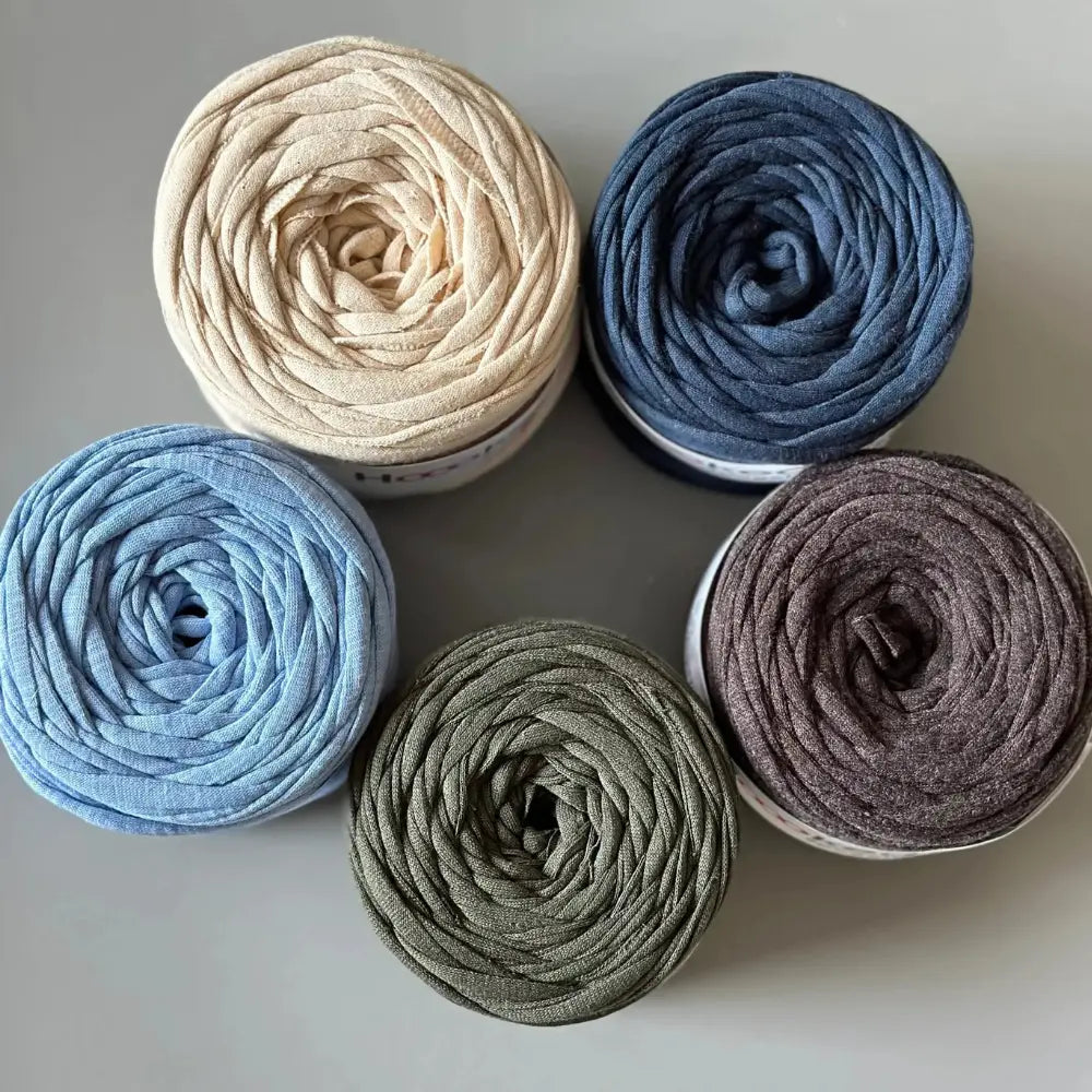 Five rolls of potholder yarn in beige, blue, gray, and brown on a light gray background