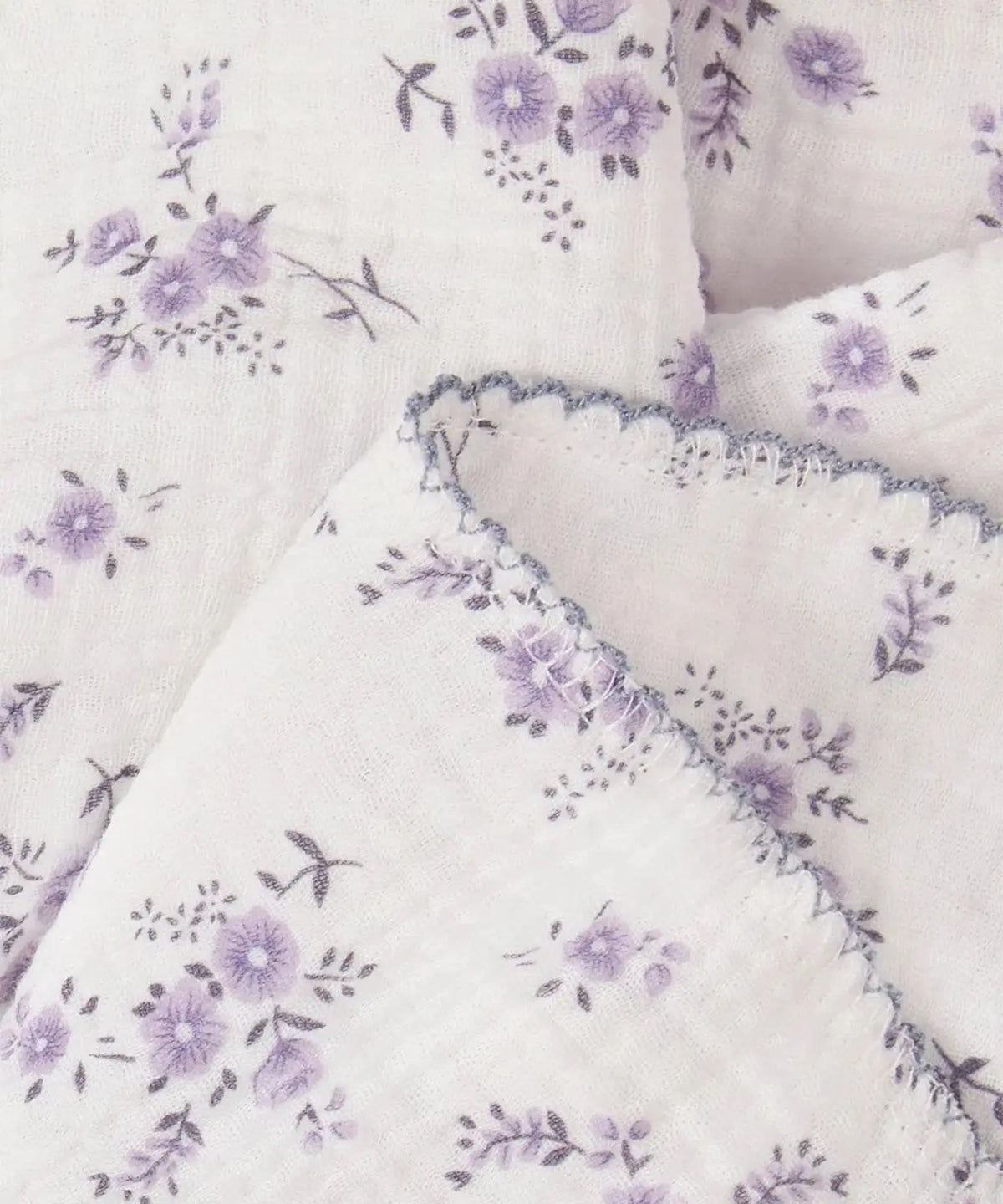 Lavender floral 100% cotton baby swaddle blanket softly draped to show its lightweight texture