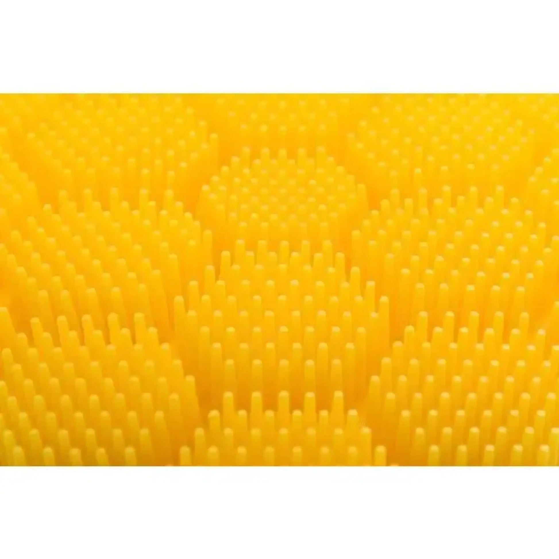 Close up of the yellow raised textured surface of the soft silicone scrubber for cradle cap, hair washing, hand washing for children