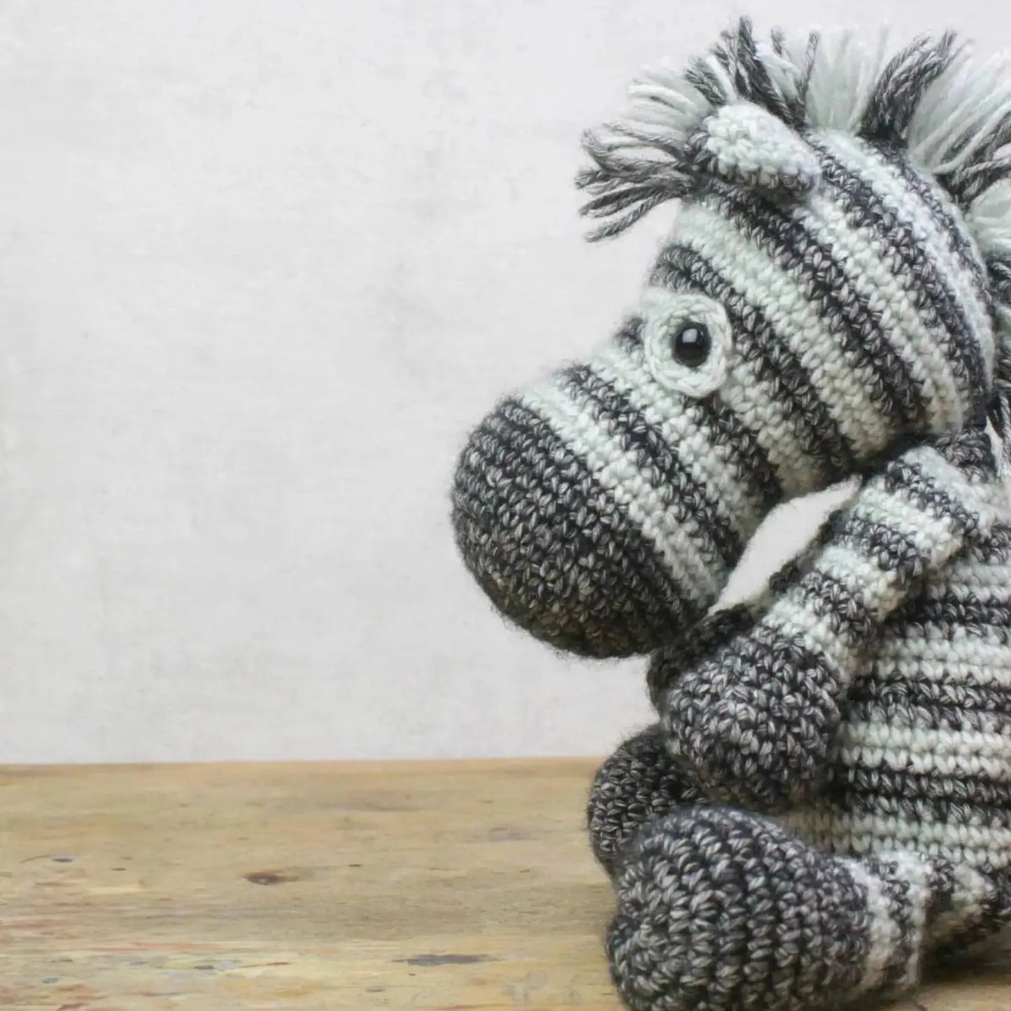 Side view of handmade crocheted zebra soft toy with striped yarn