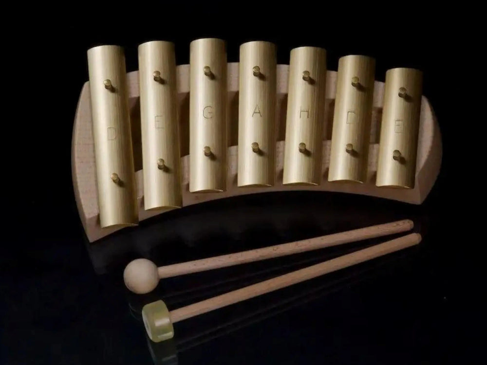 Wooden musical glockenspiel with brass bars on a black background with two mallets