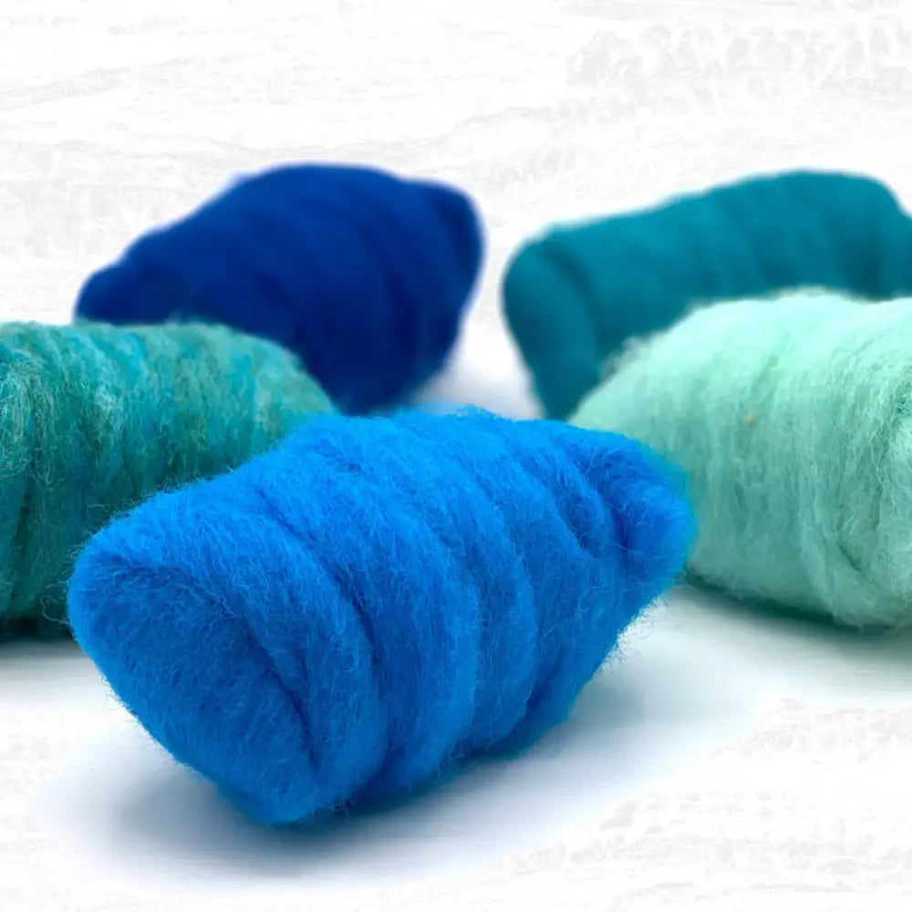 Three skeins of blue and green corriedale wool sliver on a white background