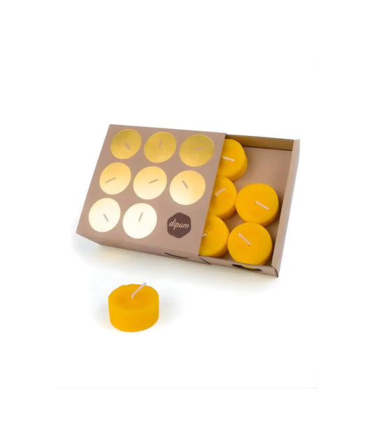 Set of yellow beeswax candles in a cardboard box on a white background