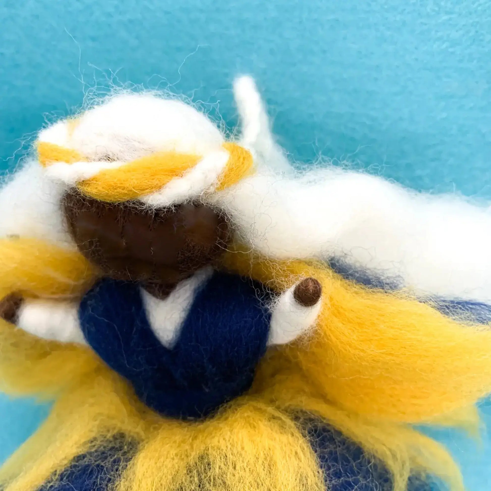 Felted fairy doll with yellow, white, and blue colors on a blue background