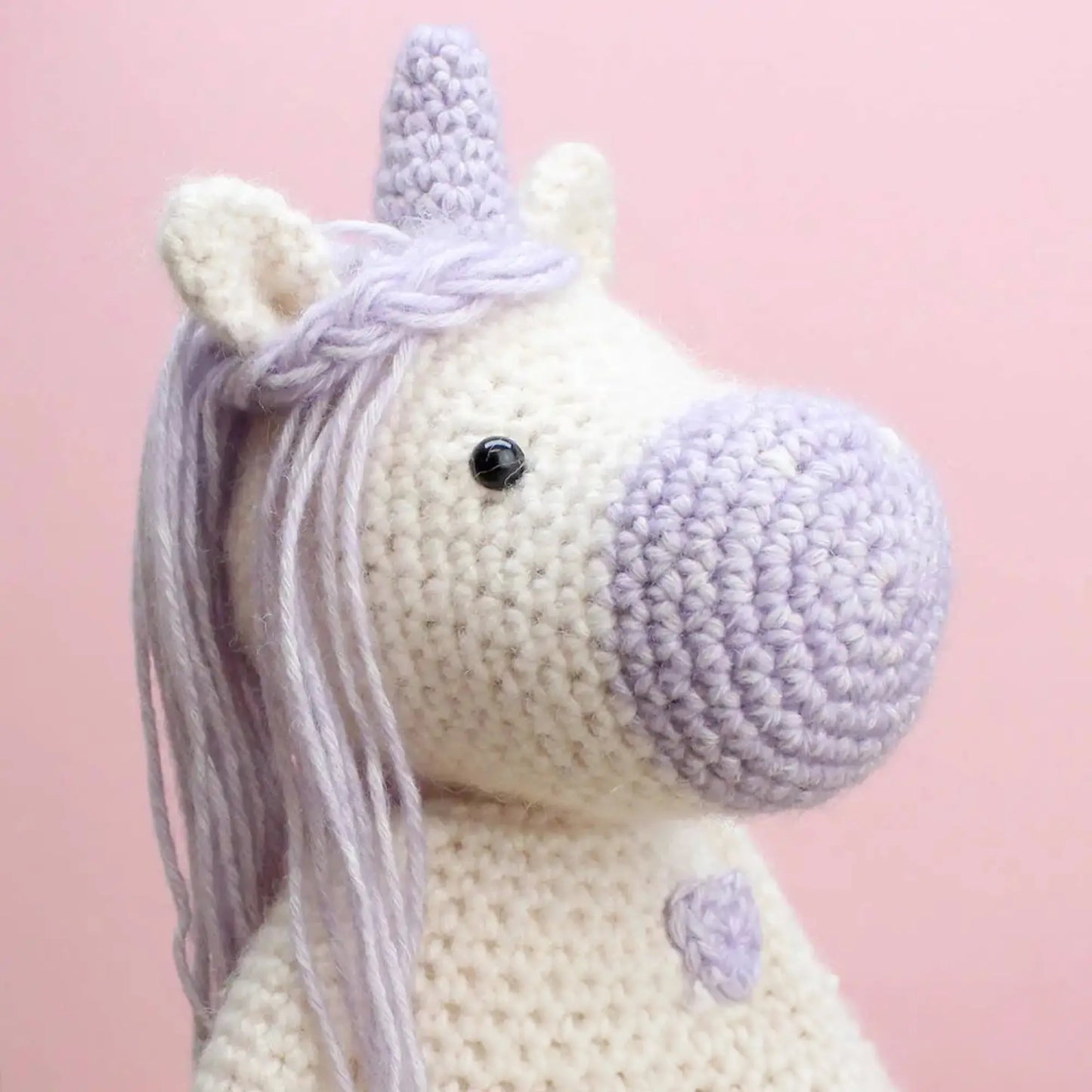 Close-up of finished crocheted unicorn soft toy with lavender mane and horn